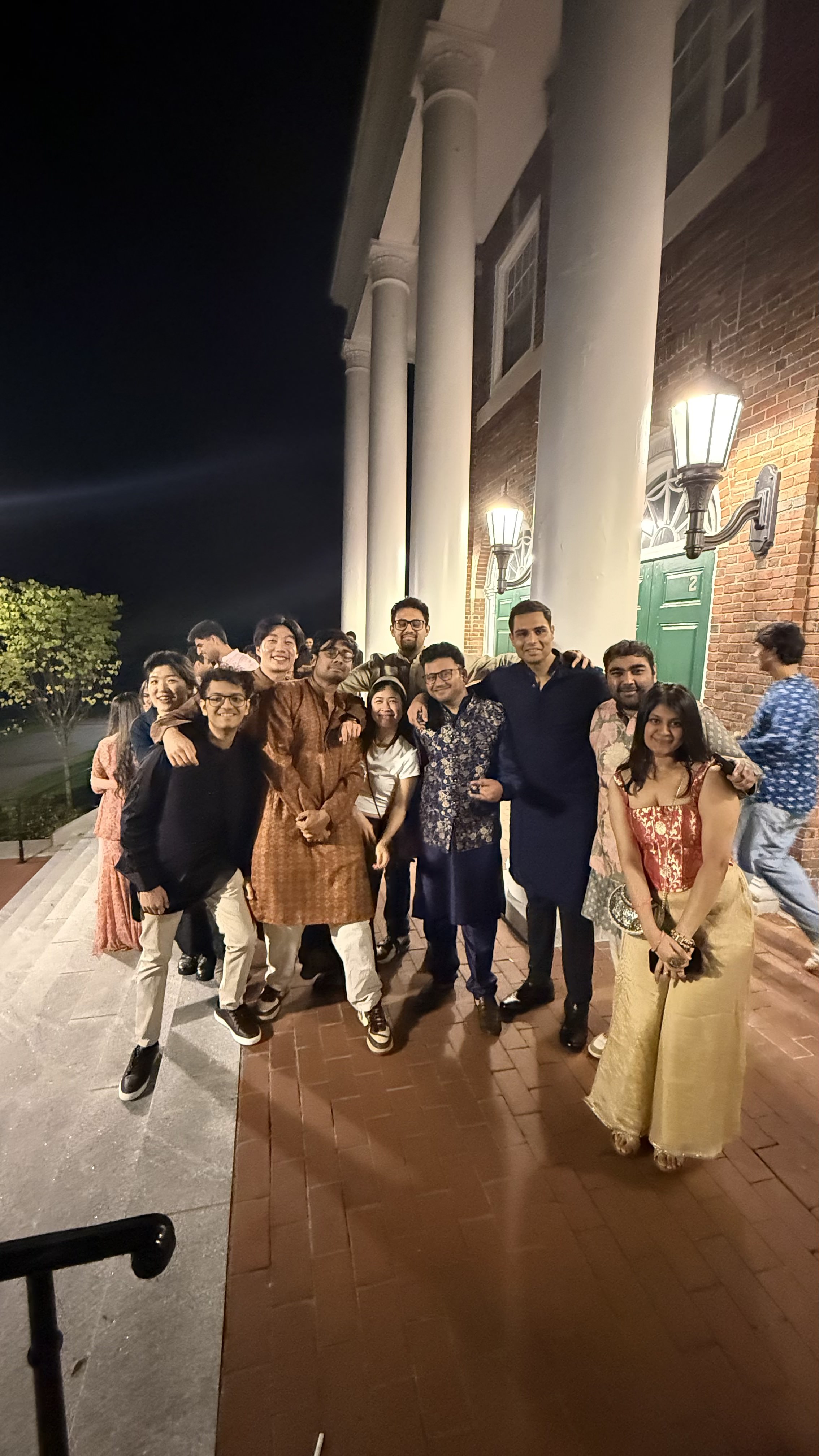 Group in traditional South Asian attire outside a Babson building at night
