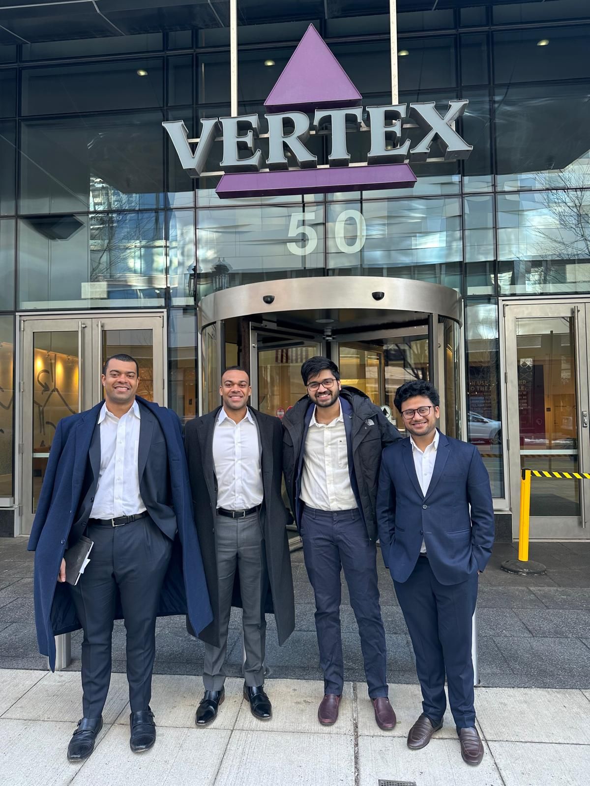 Four students in business suits outside Vertex Pharmaceuticals headquarters